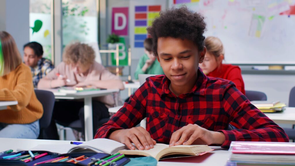 A student sits at his desk, reading and taking notes.