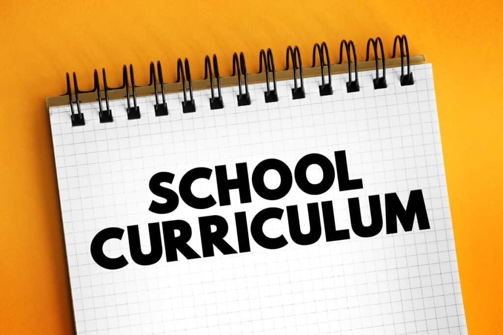 A pad of paper has the words, “school curriculum” written on it.