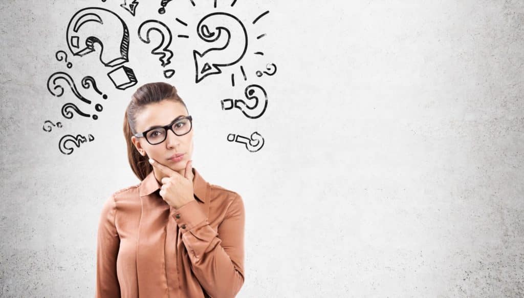 Woman standing with think cloud of question marks.