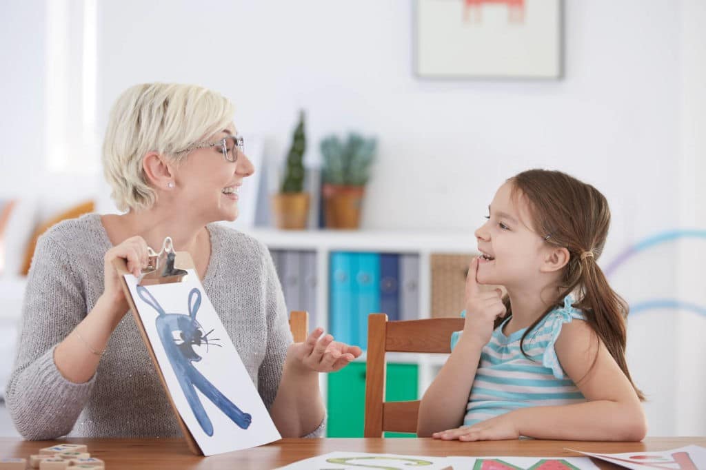 Female teaching holding up a drawn picture for a young student