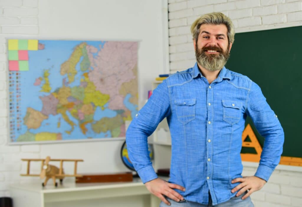 A history teacher stands smiling in front of classroom