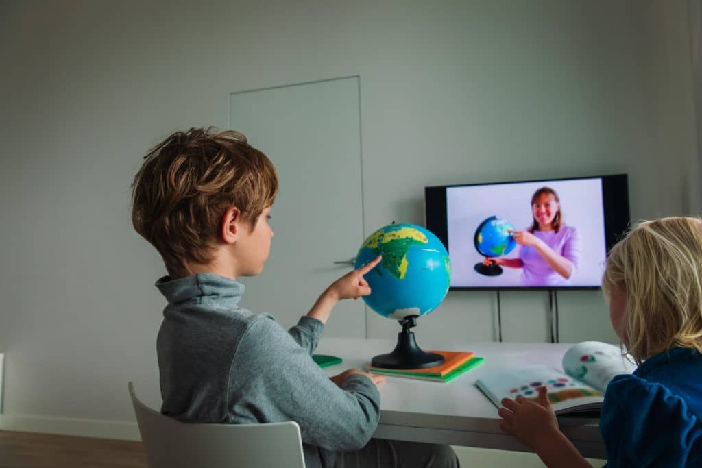 Young boy pointing to a globe during a Zoom class.