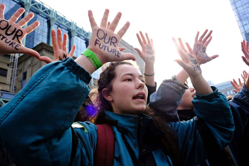 Group of students protesting outside with their hands up.