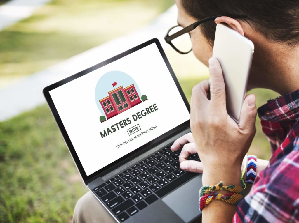 A man looks at his laptop, viewing an online master’s degree.