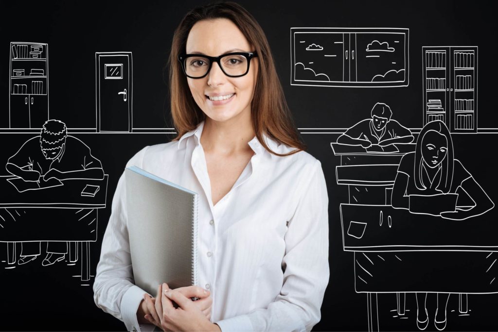 A teacher professional stands in front of a sketch of a classroom filled with students learning.