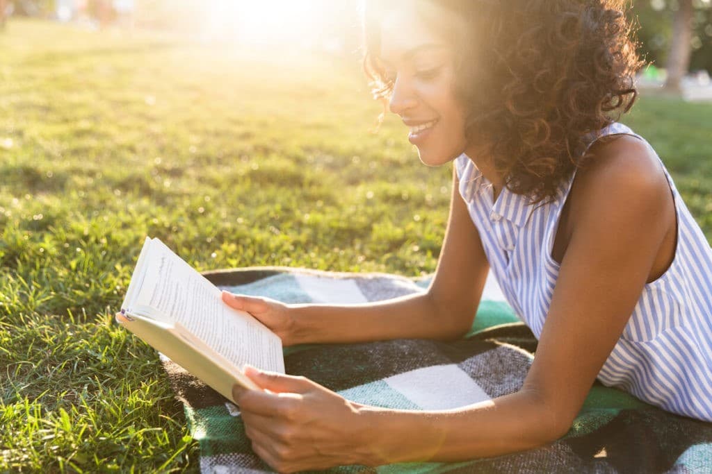 Beautiful young lady sitting outside reading a book.