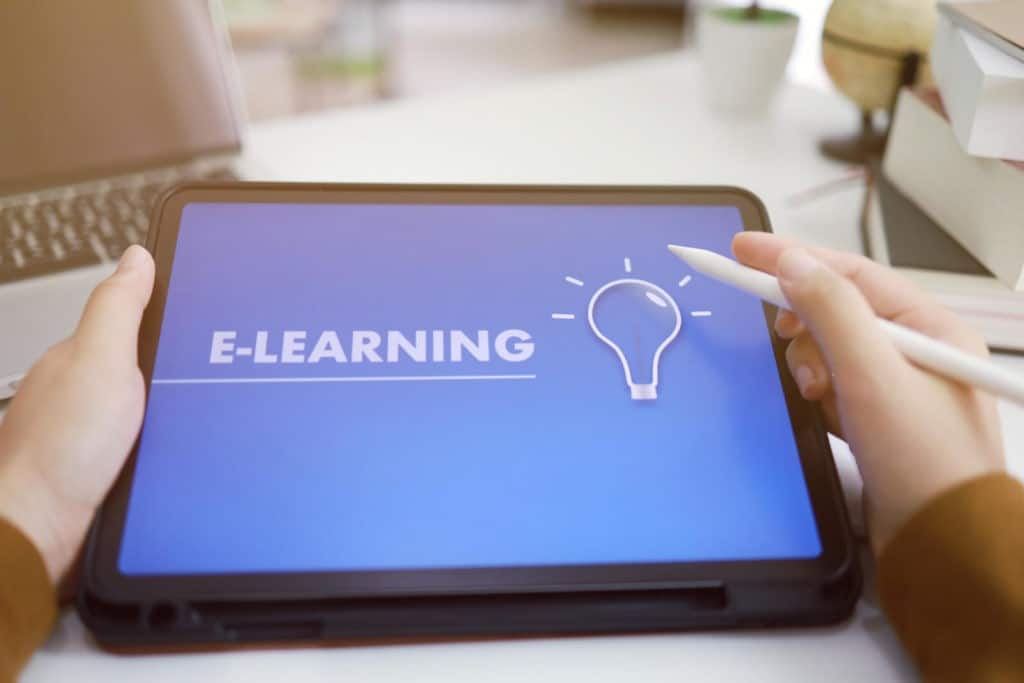 Someone holding a tablet with ‘e-learning’ on the screen.