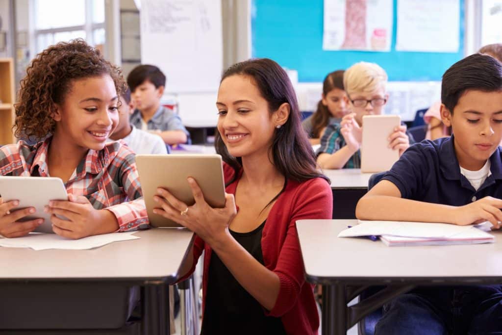 Teacher speaking to a student while holding a tablet