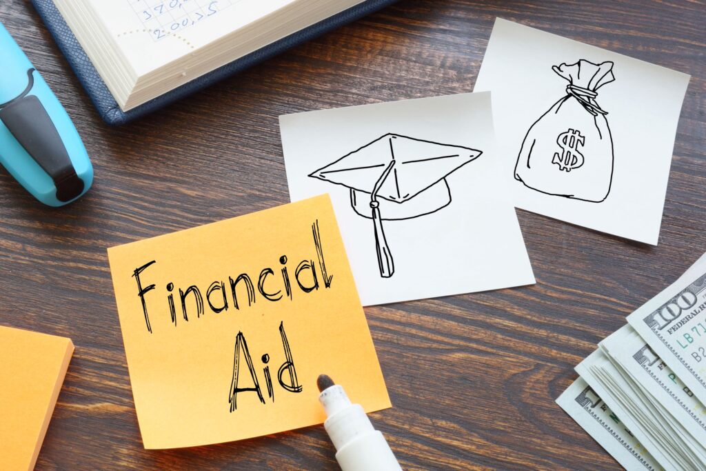 Three Post-It notes lay side by side with doodles of a bag of money, graduation cap, and one that says: “financial aid.”