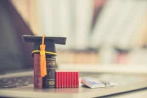 M.Ed. in Special Education; a stack of tiny books sits on a laptop with a graduation cap on top.