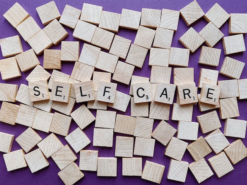 ‘Self Care’ spelled out in wooden tiles surrounded by blank wooden tiles.