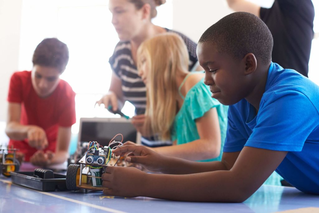Students in an after-school computer coding program learn how to build and program a robot vehicle.