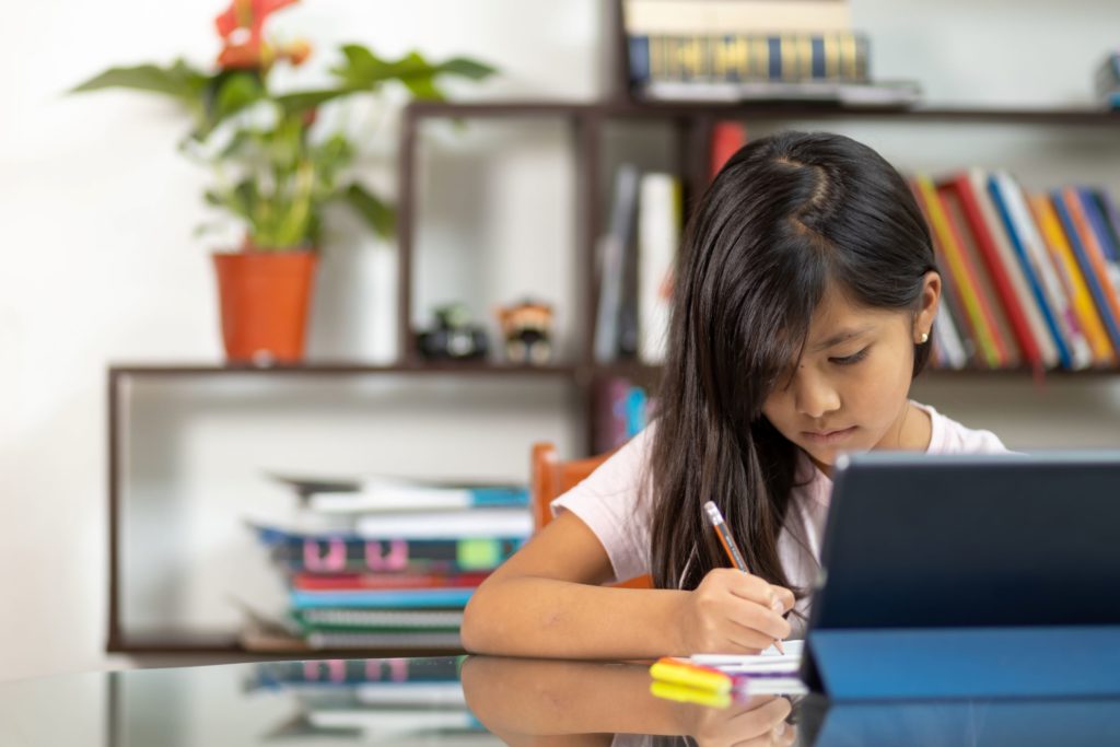 A young girl studies and writes in her notebook.