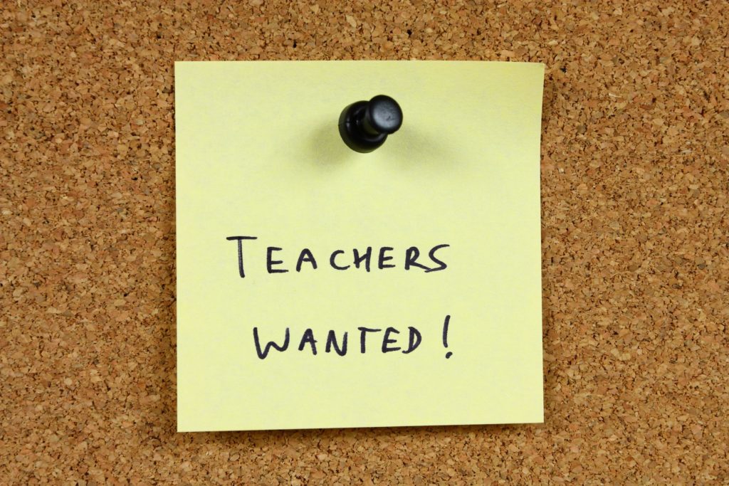 A yellow post-it note reads “teachers wanted.”