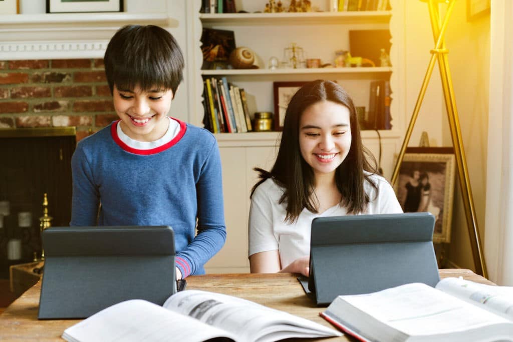 Two siblings working at a desk together during online learning.
