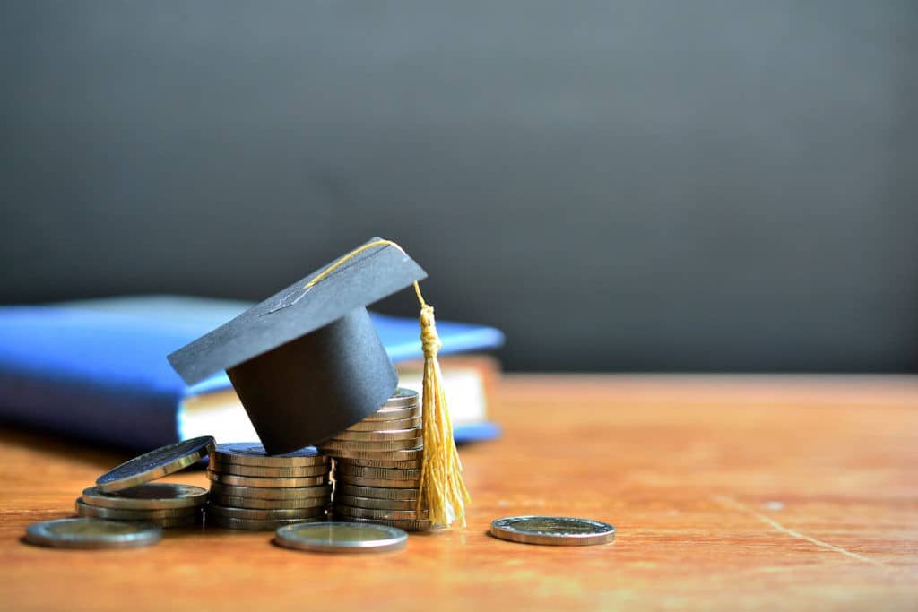Mini graduate cap sitting atop a stack of coins.